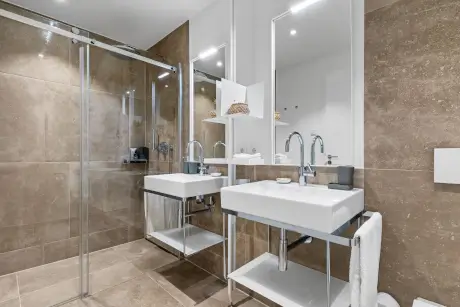 Modernes Badezimmer im Hotel Stadt Hamburg mit eleganten Waschbecken und Glasdusche.