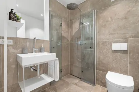 Modernes Bad mit Dusche, stilvollem Waschbecken und WC.