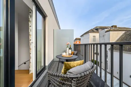 Genießen Sie den Blick von einem Balkon mit Wicker-Stühlen und einem Tisch mit Wein und Blumen.