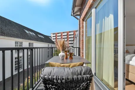 Gemütlicher Balkonblick mit einem modernen Tisch und stilvollem Dekor, einschließlich Vasen und einem bequemen Stuhl.