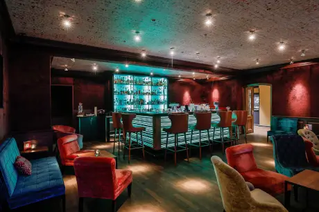 Stylische Hardy’s Bar im Hotel Stadt Hamburg mit bunten Sitzgelegenheiten und beleuchteten Regalen.