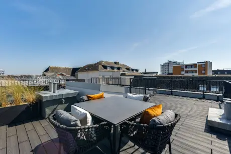 Dachterrasse mit Blick auf umliegende Gebäude und Pflanzen.