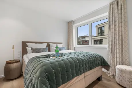 Modernes Hotelzimmer mit Bett, Fenster und Wasserflasche.