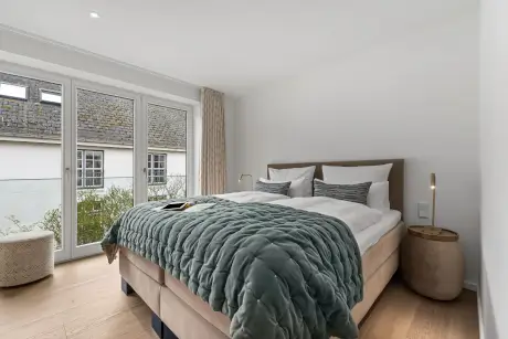 Gemütliches Hotelzimmer im 12.18. Hotel Stadt Hamburg, Westerland, Sylt mit einem großen Bett und Fenster.