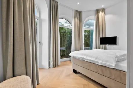 Elegantes Hotelzimmer mit Bett, Fenster und Fernseher in Westerland, Sylt.