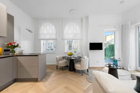 Stylisches Wohnzimmer mit moderner Küche, runder Esstisch und gemütlicher Couch.