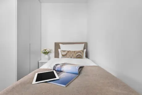 Gemütliches Hotelzimmer mit Bett, Blumenvasen, Zeitschrift und Tablet für entspannende Nächte.