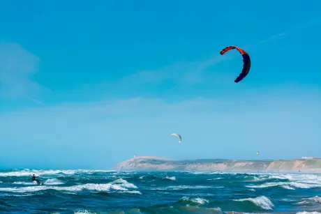 Kitesurfer skatet über das Wasser vor der Küste von Sylt mit bunten Kites in der Luft.