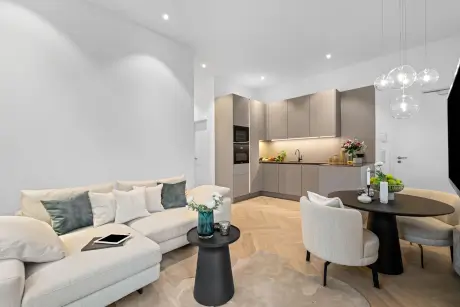 Modernes Hotelzimmer mit einer gemütlichen Couch, eleganter Küche und stilvollem Essbereich.