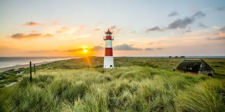 Leuchtturm bei Sonnenuntergang in Westerland, Sylt umgeben von üppigem Gras.