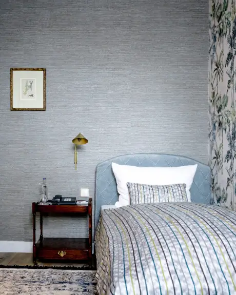 Gemütliches Hotelzimmer mit Bett, Lampe und kunstvoller Dekoration im Hotel Stadt Hamburg in Westerland.