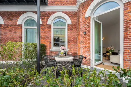 Terrasse mit Tisch und Stühlen, umgeben von Sträuchern, Gebäudefassade in Westerland/Sylt.