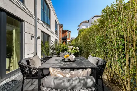 Ein schöner Gartenterrasse mit Tisch, Stühlen und dekorativen Pflanzen.