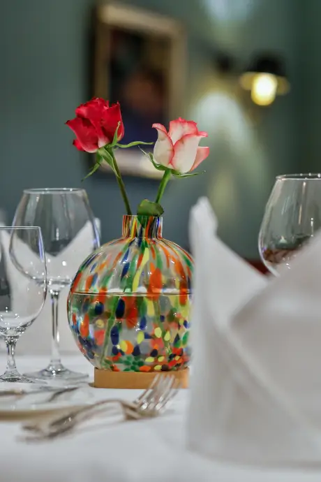Bunter Vase mit Rosen auf einem schön gedeckten Tisch im 12.18. Hotel Stadt Hamburg.